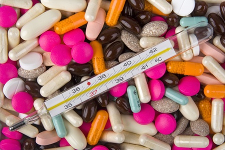 Pills and thermometer on white background.