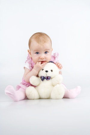 Child with plushy cuddle-bear and by two fingers in mouth,on white background.の写真素材