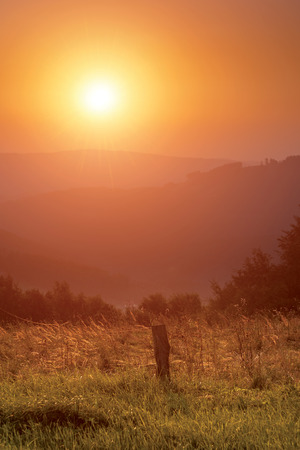 Sunrise over a meadow in mountainsの写真素材