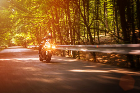 Biker riding on a forrest road during sunsetのeditorial素材