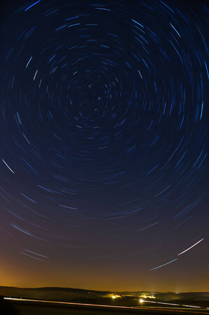 View of a field at night with star trails in the skyの写真素材