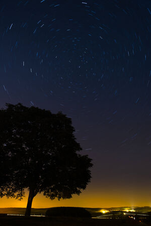 View of a field at night with star trails in the skyの写真素材