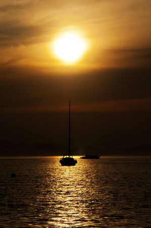 Sun goes down over a sea bay with boat in Adriaticの写真素材