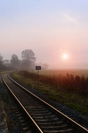 Railroad track during autumn foggy morning in countrysideの写真素材