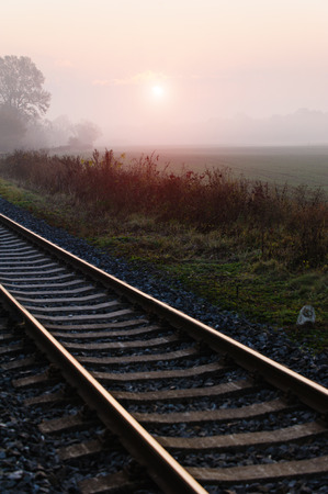 Railroad track during autumn foggy morning in countrysideの写真素材
