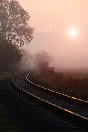 Railroad track during autumn foggy morning in countrysideの写真素材