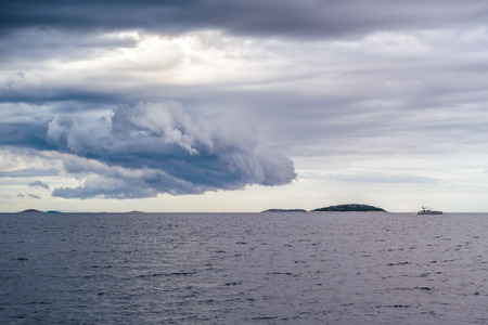 Heavy rain cloud above a deserted island and motor yachtの写真素材