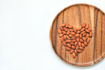 Salted  roasted almonds on wooden dish and white backgroundの写真素材