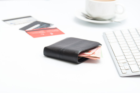 Money bag with keyboard and cup of coffe on white backgroundの写真素材
