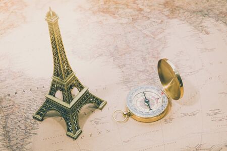 Vintage Film Look, Eiffel tower miniature with compass on world map, blurred copy space / soft focusの写真素材