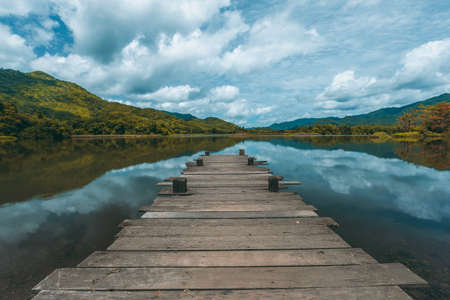 view of the wooden pier in the lake with mountain scenery background. in the early morning.