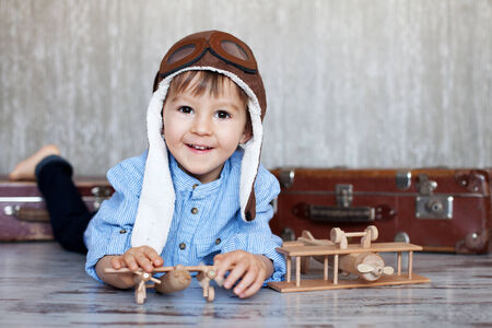 Little boy, playing with wooden planes, indoor, sitting on a suitcase の写真素材