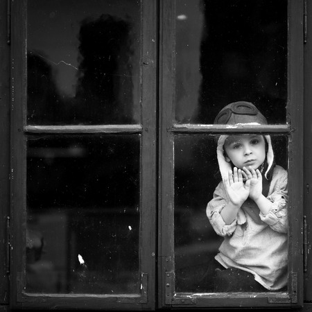 Boy on the window, smiling and drinking tea, having fun の写真素材