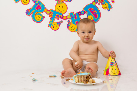 Little baby boy with birthday cake, smashing itの写真素材