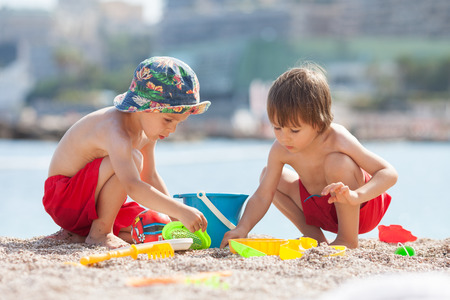 Two cute kids, playing in the sand on the beachの写真素材