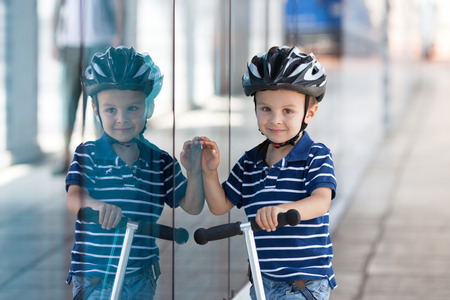 Cute boy, riding a scooter, reflection on windowの写真素材