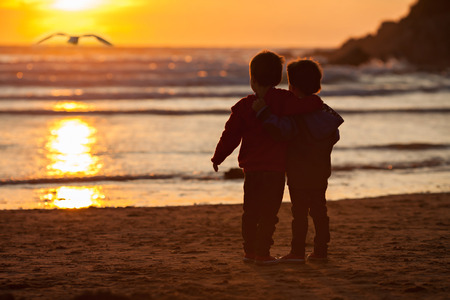 Beautiful picture of two boys on the beach at sunsetの写真素材