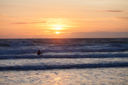 Surfer on the ocean beach at sunsetの写真素材
