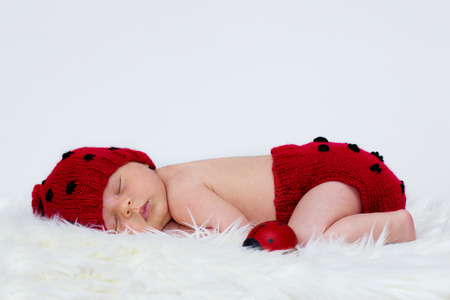 Baby boy in a ladybug hat and pantsの写真素材