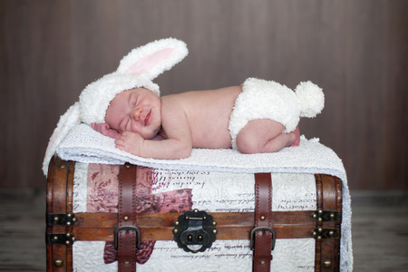 Adorable baby boy, sleeping on a trunk, dressed like bunnyの写真素材