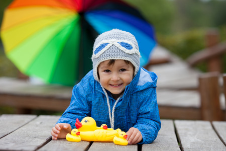 Adorable little boy, playing with rubber ducks outside on an autumn day in the park