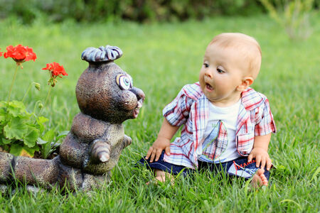 Little boy, making funny faces on a statue in a garden