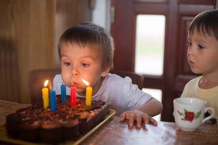 Adorable five year old boy celebrating his birthday and blowingの写真素材