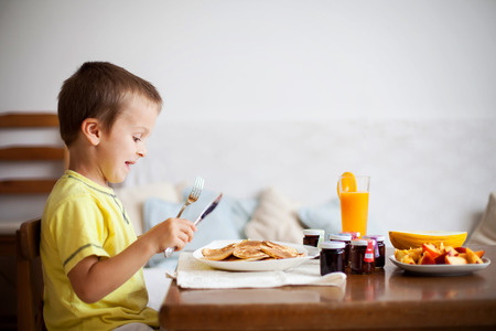 Cute boy, eating pancakes at homeの写真素材