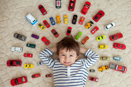 Adorable boy, lying on the ground, toy cars around him , looking at the camera, shot from aboveの写真素材