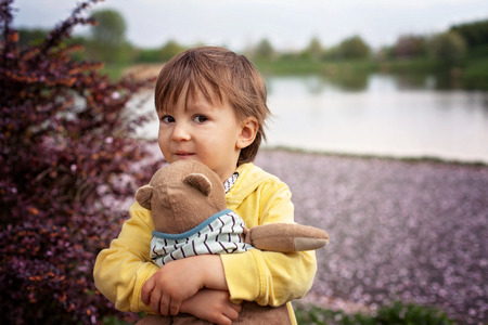 Adorable little boy, holding toy friend in a park, springtimeの写真素材