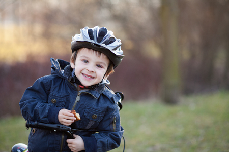 Little boy with helmet and bike, eating cakeの写真素材