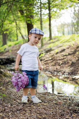 Boy with a lilac and a cage on a pondの写真素材