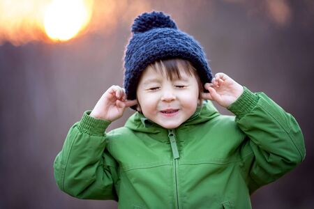 Cute little boy, holding his hands over ears not to hear, making sweet funny faceの写真素材