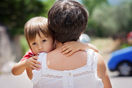 Grandmother, holding and hugging her grandson, little cute caucasian boy, outdoors, tender portraitの写真素材