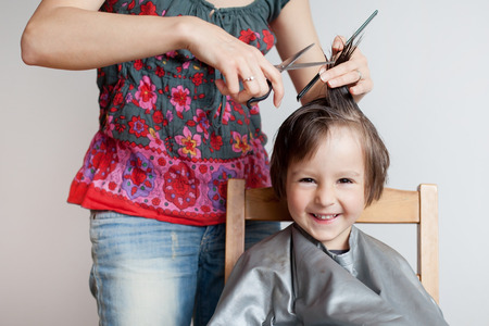 Cute little boy, having haircut, smiling happily, white backgroundの写真素材