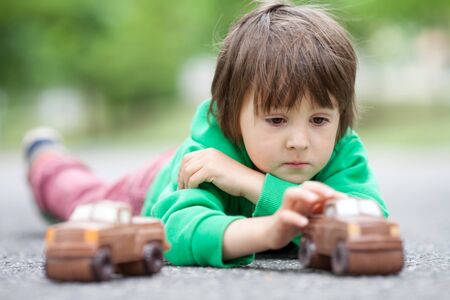 Funny little boy playing with car of chocolate, outdoor, having funの写真素材