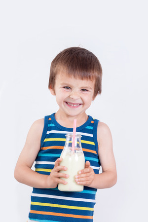 Cute little boy, drinking milk, holding glass of milk, mustaches from the milkの写真素材