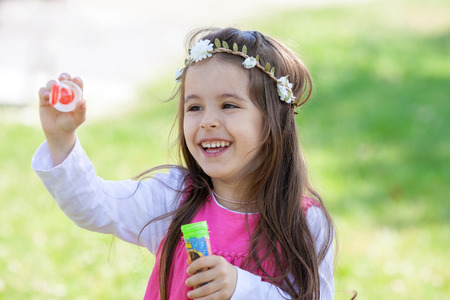 Beautiful portrait of sweet lovely little girl blowing soap bubbles in the park, summertimeの写真素材