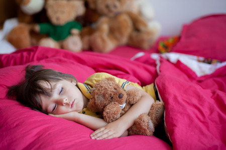 Sweet little boy, sleeping in the afternoon with his teddy bear toyの写真素材