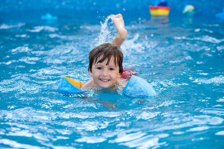 Sweet little boy, swimming in big swimming pool, summrtime