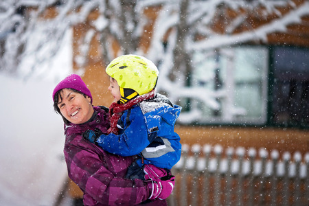 Young grandmother and her little toddler grandson, playing in the snow, colorful clothing