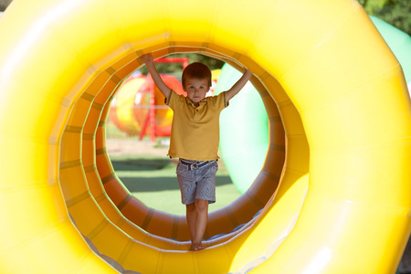 Cute little boy, playing in a rolling plastic cylinder ring, full with air, outdoorの写真素材