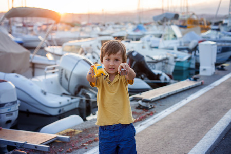 Happy cute little child, boy, playing with helicopter on a port on sunset, summertimeの写真素材