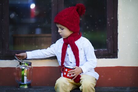 Cute little boy, holding cup with tea, waiting for Santa impatientlyの写真素材