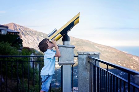 Curious boy, looking through a telescope at something interesting, summertimeの写真素材