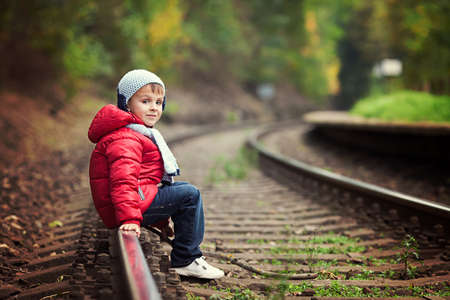 Cute boy walking on a railroad, smiling, autumn timeの写真素材