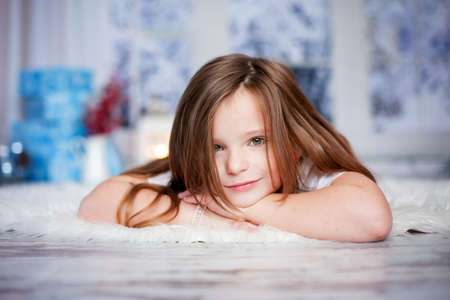 Beautiful winter close portrait of little preschool girl at home, dreamingの写真素材