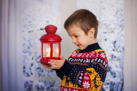 Sweet child, holding lantern at home on a snowy day, wintertimeの写真素材