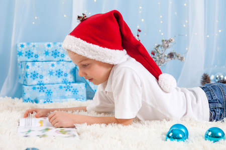 Sweet boy, reading a book on Christmas, decoration around him, studio shotの写真素材