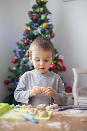Cute little boy, playing with modeling dough, molding figures at home on Christmasの写真素材